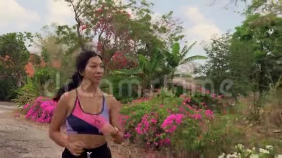 在小径上慢跑的年轻充满异国情调和美丽的亚洲印尼妇女用多乐风格拉回万向节的镜头视频的预览图