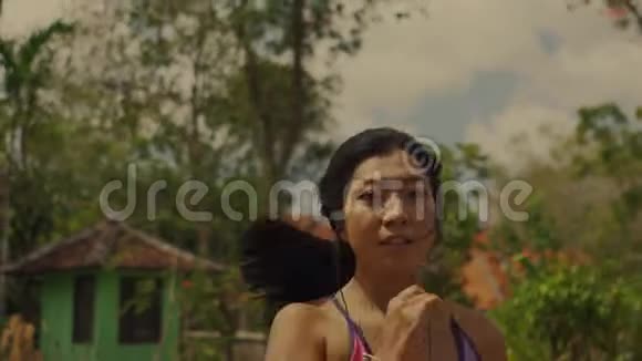 在小径上慢跑的年轻充满异国情调和美丽的亚洲印尼妇女用多乐风格拉回万向节的镜头视频的预览图