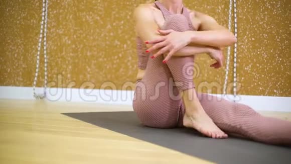 年轻女子坐在垫子上在瑜伽馆伸展身体视频的预览图