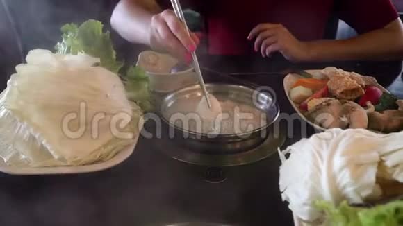 手把蔬菜和肉放进火锅里吃中餐馆视频的预览图
