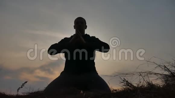 宗教观念一位在日落阳光下冥想的男僧的剪影日落时分的佛教祈祷健康视频的预览图