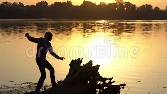 在金色的夕阳下一个虔诚的人在湖畔跳舞视频的预览图
