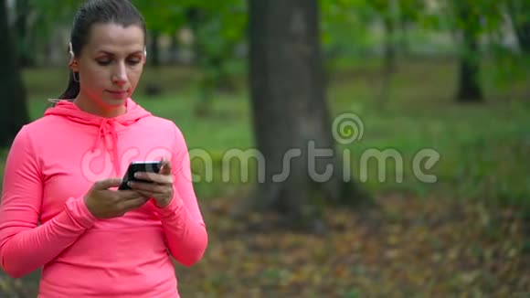接近女人选择音乐在日落时穿过一个秋天的公园慢动作视频的预览图