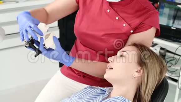 女牙医向年轻女性病人展示和解释石膏模型的问题视频的预览图