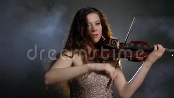 在爱乐乐团的烟雾中演奏小提琴的长发小提琴手视频的预览图