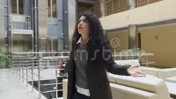 迷人的黑发女人和镜头谈论她站的建筑视频的预览图