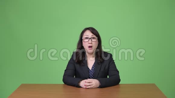 成熟美丽的亚洲女商人坐在办公桌后头痛视频的预览图