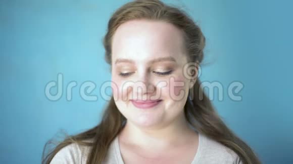 蓝色背景上美丽的白种人女子微笑镜头青春快乐视频的预览图