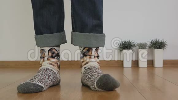 一个穿暖和羊毛袜的人的腿的特写站在房间的木地板上踩着视频的预览图