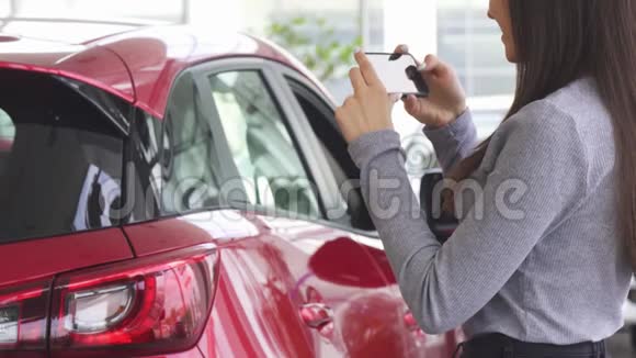 一个女人在拍她的新车的照片时视频的预览图