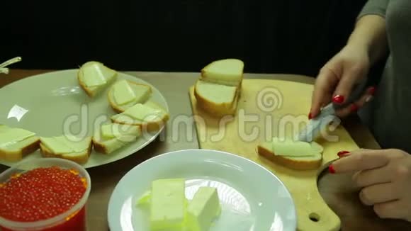 一个女人用鱼子酱在面包上切黄油做罐头视频的预览图