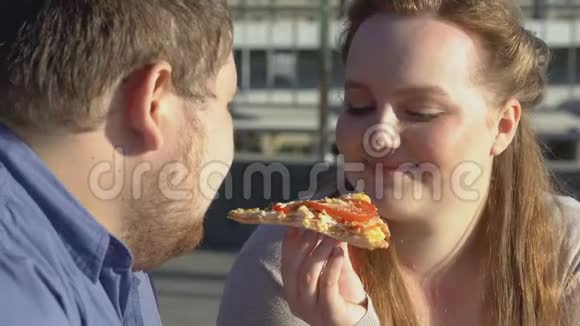 微笑肥胖夫妇享受披萨的味道食物的热情超重问题视频的预览图