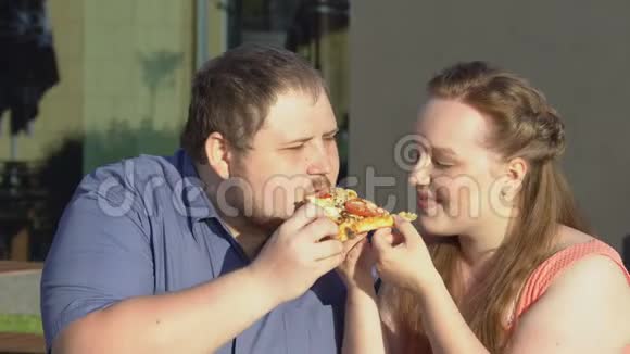 爱的一对夫妇一起咬披萨片不健康的户外零食懒惰的休闲视频的预览图