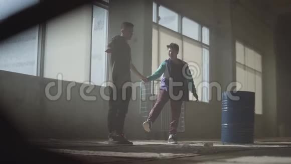 两个年轻人在废弃建筑的黑暗和尘土飞扬的房间里跳舞同时跳舞的青少年视频的预览图