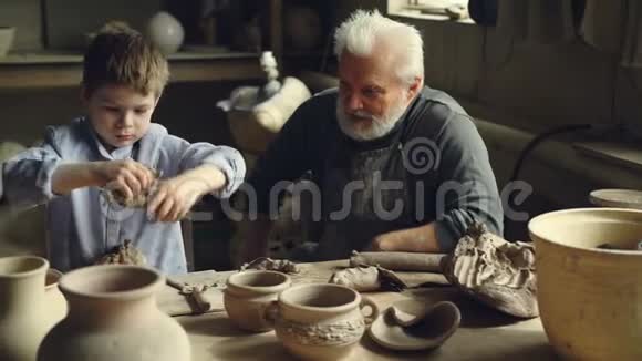 孩子正在学着用粘土工作一边和祖父一起在陶器里玩一边玩着捏泥视频的预览图