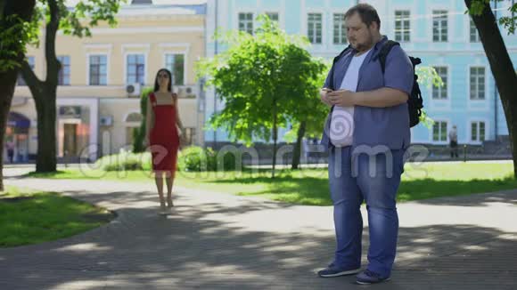 肥胖男性悲伤地看着穿着漂亮苗条的女士外表不安全视频的预览图