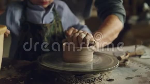 特写镜头四手爷爷和孙子一起在纺抛轮上成型陶瓷锅陶器视频的预览图