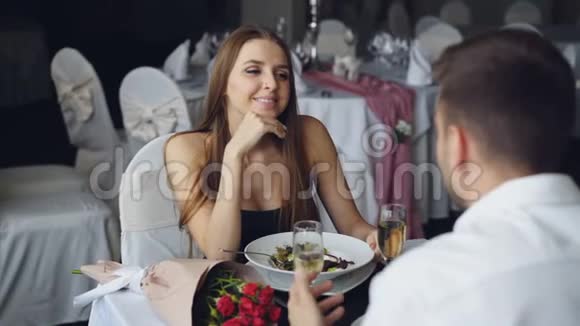 穿着漂亮衣服的开朗的女孩和男朋友说话在餐馆一起吃饭时大笑视频的预览图