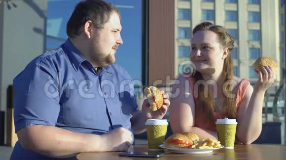 在户外浪漫约会卡路里和饮食中超大型夫妻共享汉堡视频的预览图