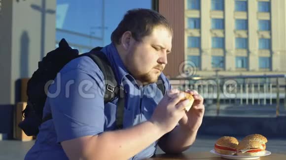 超重男性咀嚼汉堡不健康的办公室午餐消化问题视频的预览图
