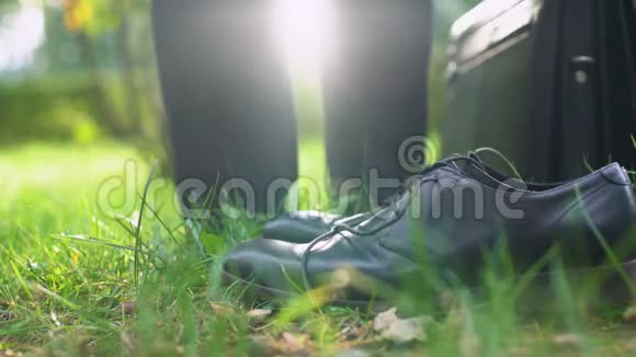 办公室工作人员把鞋子和公文包留下光着脚走在绿草上视频的预览图