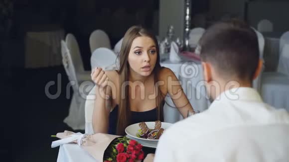 愤怒的年轻女人在餐馆吃饭时和她的爱人吵架大喊大叫和打手势花束视频的预览图
