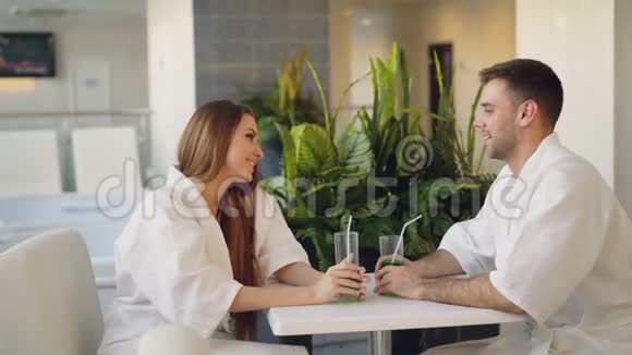 快乐的年轻人正在聊天在白天的温泉里坐在桌子旁喝着鸡尾酒杯舒适舒适舒适视频的预览图