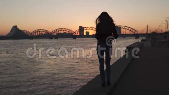 在日落时分年轻女子在多加瓦河边散步时感到自信视频的预览图