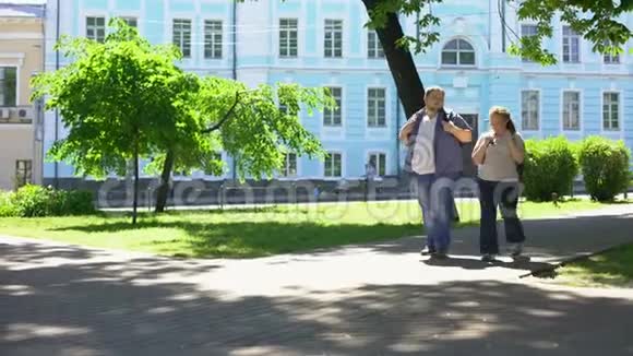 在城市公园散步的胖学生夫妇城市约会休闲时间友谊视频的预览图