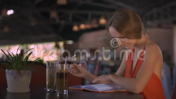 女孩在咖啡馆的日饮果汁中写作视频的预览图
