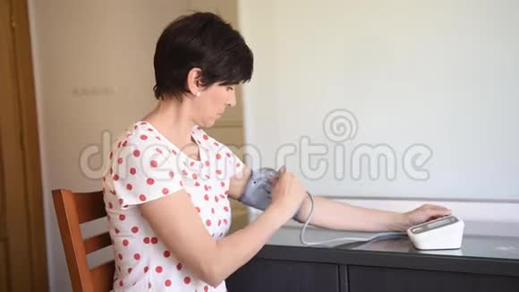 中年妇女用电子血压测量装置测量自己的血压视频的预览图