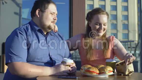 微笑的女人对待男朋友炸薯条肥胖的情侣约会不健康的食物视频的预览图