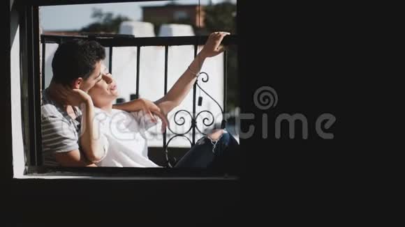 美丽的年轻多民族夫妇坐在美丽浪漫的阳光公寓阳台上欣赏风景视频的预览图