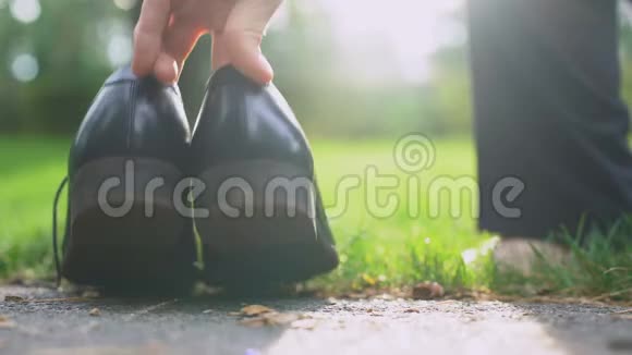 商人在绿色公园光着脚走着留下了他的鞋子和公文包视频的预览图