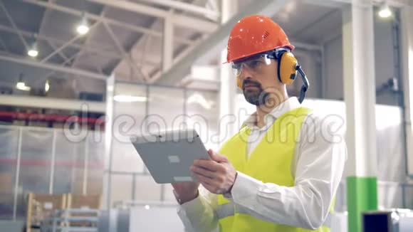 工厂工人站在一个工厂仓库里和他的平板电脑一起工作视频的预览图