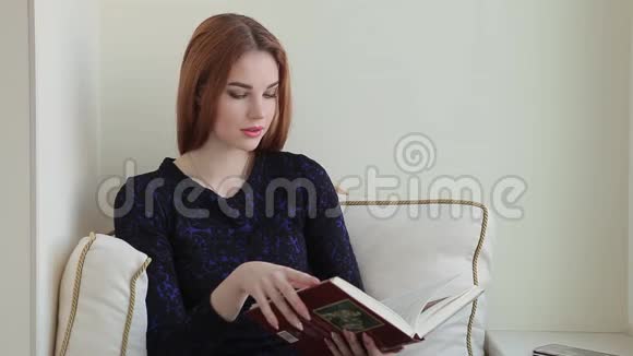 美女坐在家窗台边看书边打电话视频的预览图