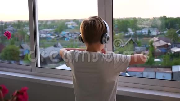 年轻人打开窗户背景模糊青少年喜欢耳机里的音乐视频的预览图