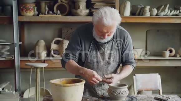 有经验的工匠正在制作陶瓷碗的耳朵并在舒适的工作场所将其固定在粘土器皿上陶器视频的预览图