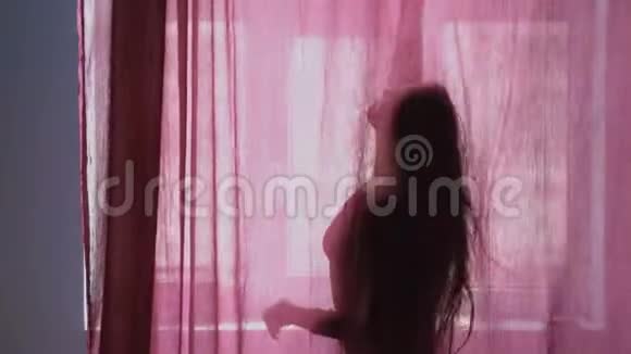 年轻女子在窗前跳舞的剪影女人在窗前跳舞视频的预览图