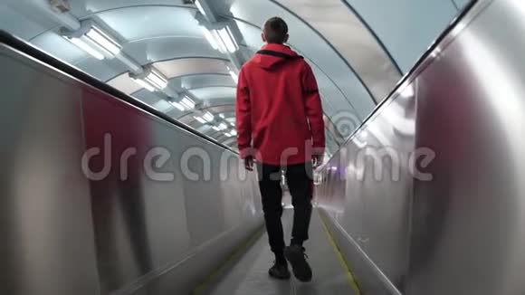 穿着红色夹克和太阳镜的有趣活跃的家伙站在自动扶梯上视频的预览图