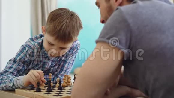 特写镜头两人父子下棋想着下一步的动作和棋手上的移动视频的预览图