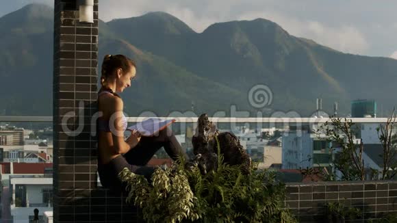 坐在露台上看镜头男人的女孩读书视频的预览图