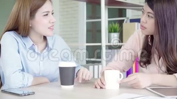 亚洲商界女性喜欢喝热咖啡讨论工作和闲聊八卦同时放松在办公室工作视频的预览图