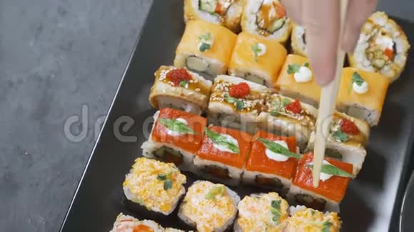 筷子的特写镜头将寿司卷在盘子或拼盘上在日本酒吧餐厅提供顶部视频的预览图