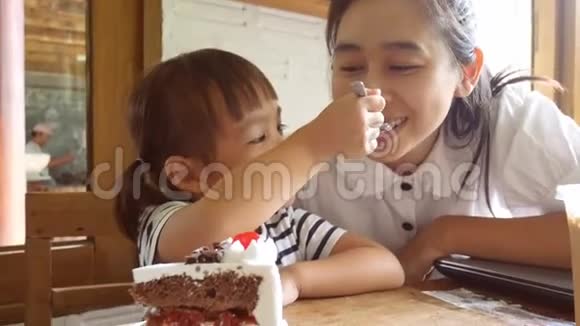 快乐的亚洲小女孩和她的母亲在咖啡馆里吃蛋糕视频的预览图