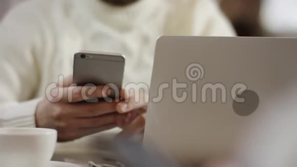 成年男子坐在笔记本电脑前在智能手机上发短信视频的预览图