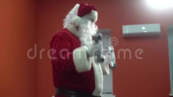 圣诞老人在健身房训练圣诞节圣诞老人正在用哑铃工作视频的预览图