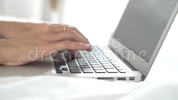 年轻的亚洲女人在卧室里用笔记本电脑休闲女孩在网上用键盘打笔记本视频的预览图