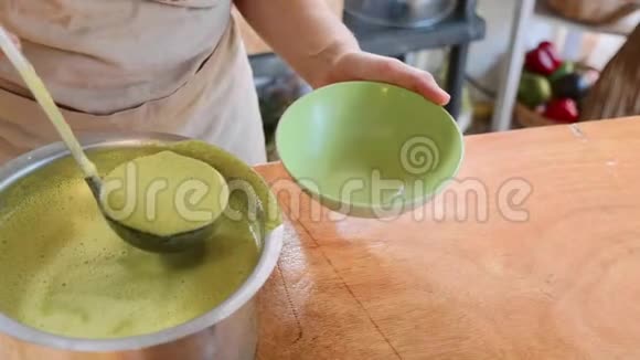 厨师用平底锅在碗里倒入一个绿色菠菜奶油汤视频的预览图