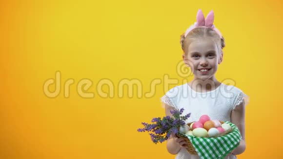 复活节快乐铭文微笑的小女孩带着鸡蛋展示篮子视频的预览图